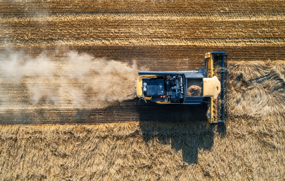 Aerial view of a combine harvester working in a golden grain field